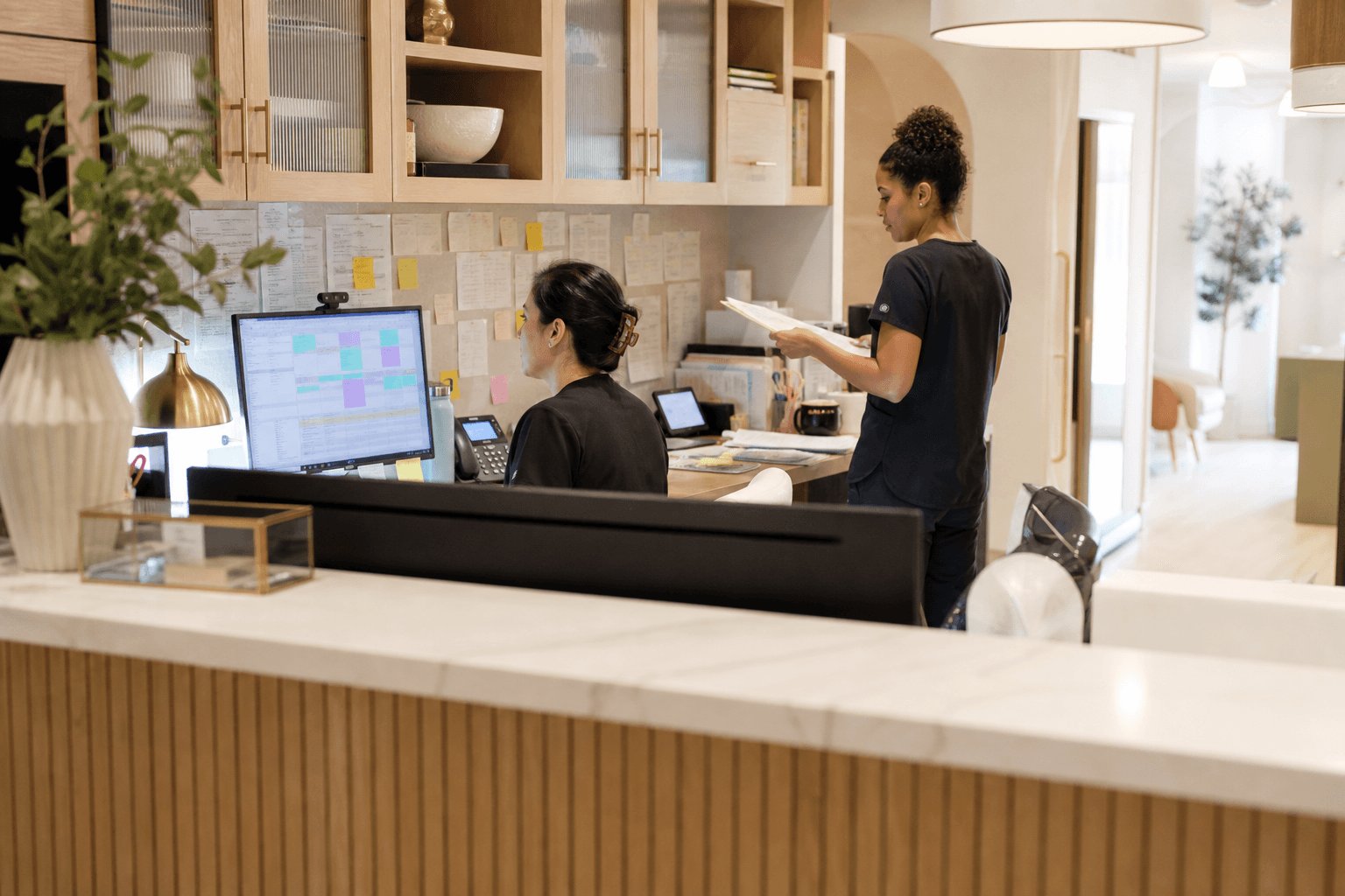 Two med spa team members coordinating schedules and paperwork at a busy front desk